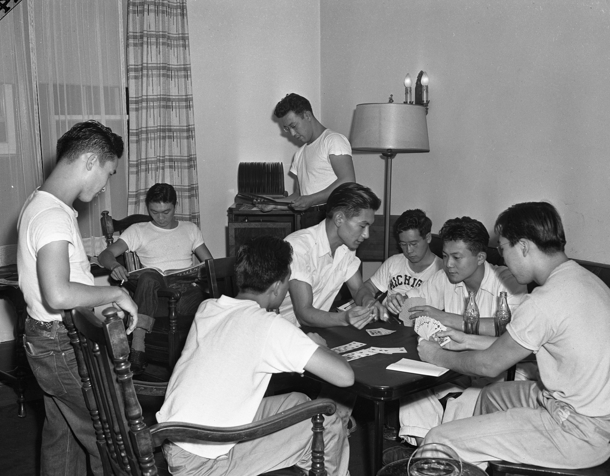 A photo of Japanese American workers at the University of Michigan gathered around a game of cards in 1943.